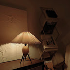 In a dim room, this Clérachic table lamp gives off a warm amber glow beside a shelf of design magazines.