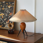 This Clérachic table lamp, unlit, stands by a bird-print panel and a vintage radio on a dark wood cabinet.