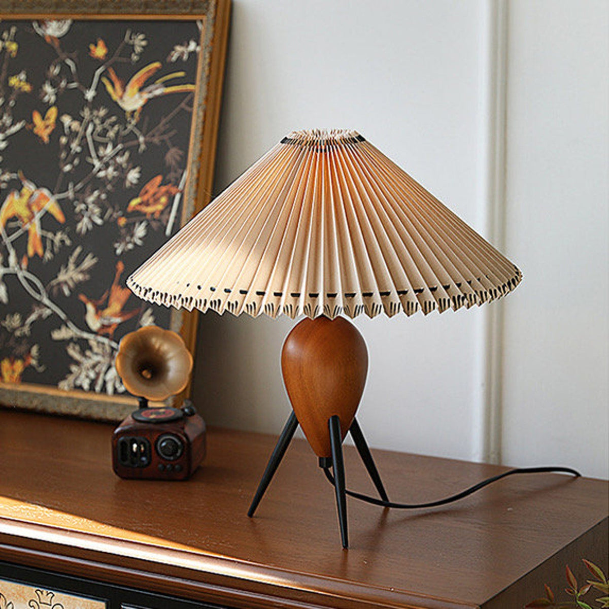 This Clérachic table lamp, unlit, stands by a bird-print panel and a vintage radio on a dark wood cabinet.