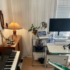 A Clérachic table lamp lights a corner of a studio, with a keyboard, a desk setup and a wall candle holder beyond.
