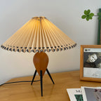 A Clérachic table lamp on a honey-toned desk, a framed portrait beside it and the black cord running off the edge.