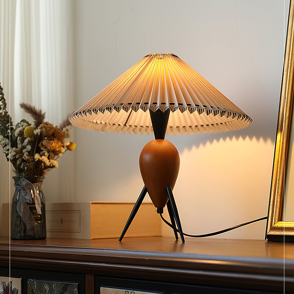Soft side light on a Clérachic table lamp on a wood shelf, with dried flowers, a pale box and a gold frame behind.