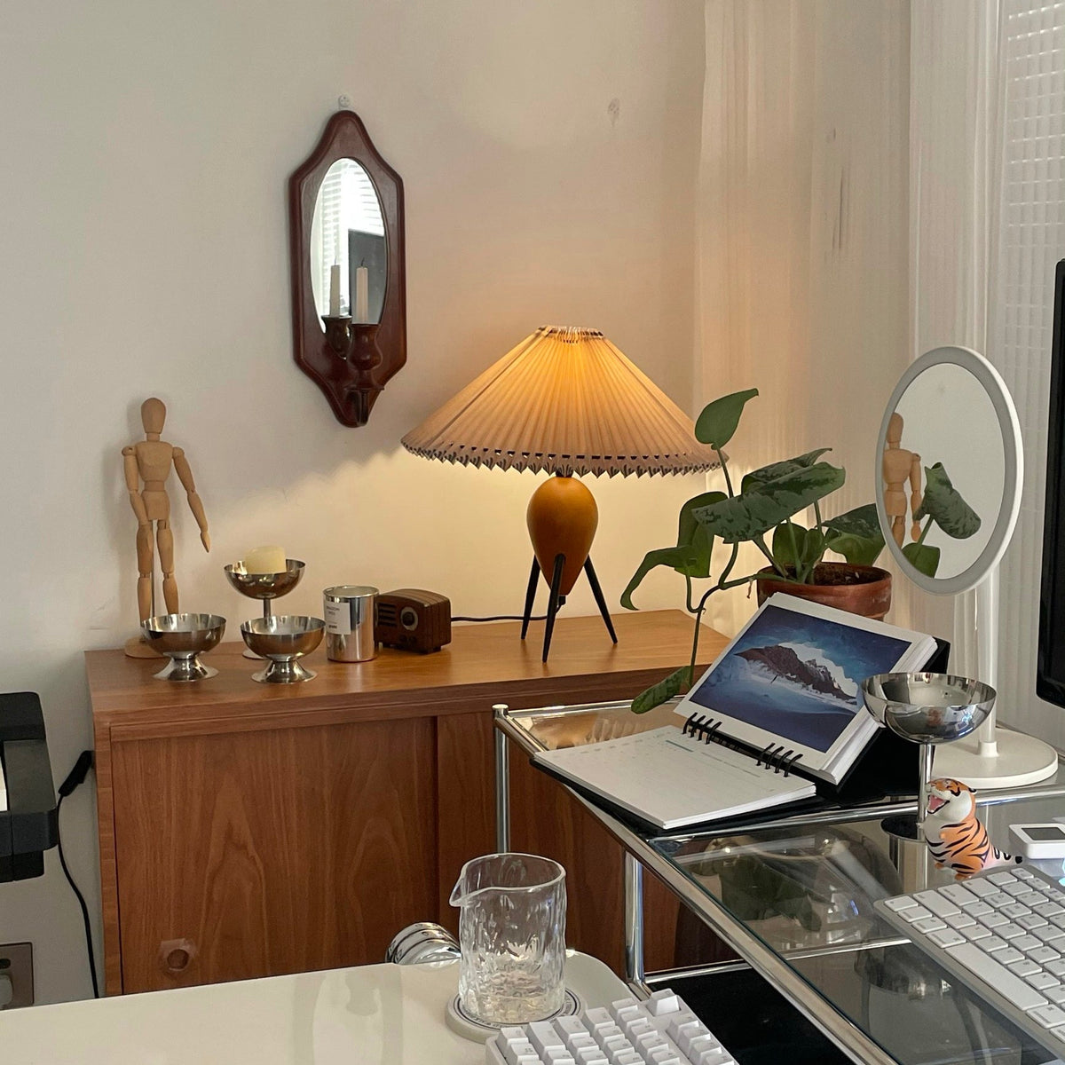 Tucked in a corner of a work desk, this Clérachic table lamp sits near a wall mirror, a laptop and silver bowls.