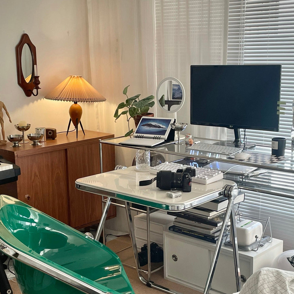 A tall Clérachic table lamp in a busy home office, with a monitor, laptop and glass desk in the background.
