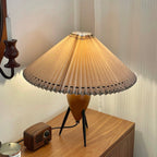 A Clérachic table lamp on a wood sideboard glows beside a small retro radio, a candle holder on the wall behind it.