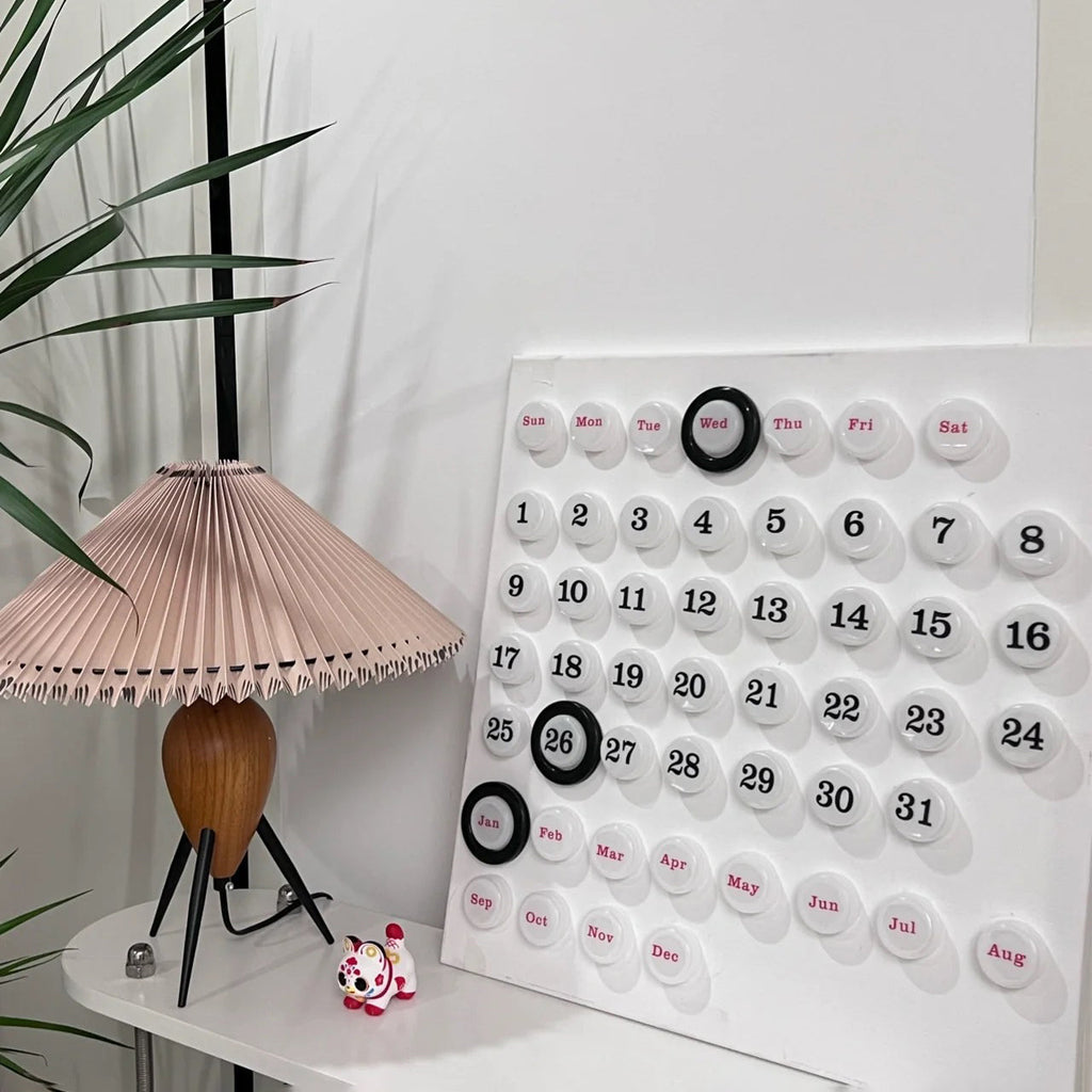 At the edge of the frame, a Clérachic table lamp stands by a big white calendar, with a small tiger figure nearby.