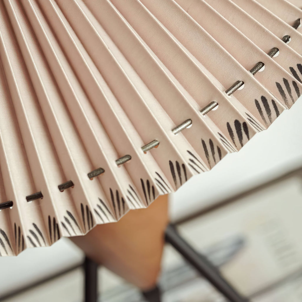 Close view of the metal staples and hand-finished pleat edge on the shade of this Clérachic table lamp.