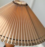 Close view of the pleats on this Clérachic table lamp shade, lit from inside with a warm peach glow.