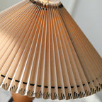 Tight view of lit pleats on this Clérachic table lamp, with a row of dark stitches along the lower hem.