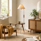 This Clérachic floor lamp with a tray table in a sunny reading corner, with a woven throw on a wooden armchair beside it.