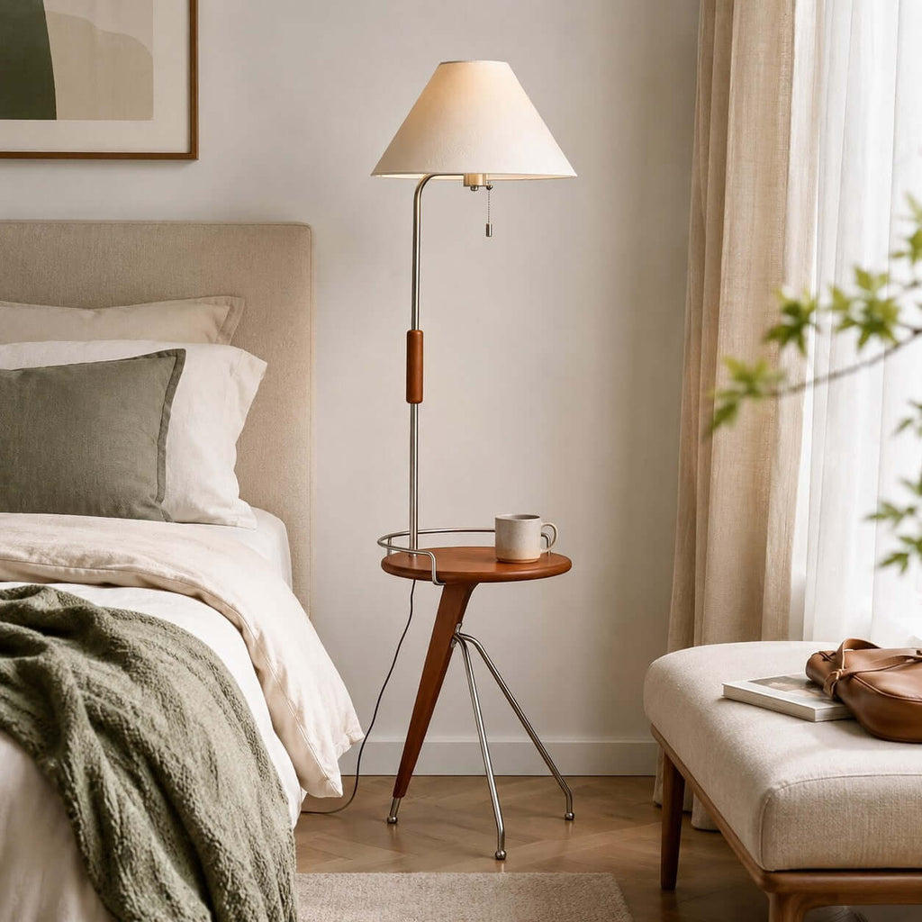 Clérachic floor lamp with a tray table and a mug, standing beside a bed with linen bedding and an olive-green throw.
