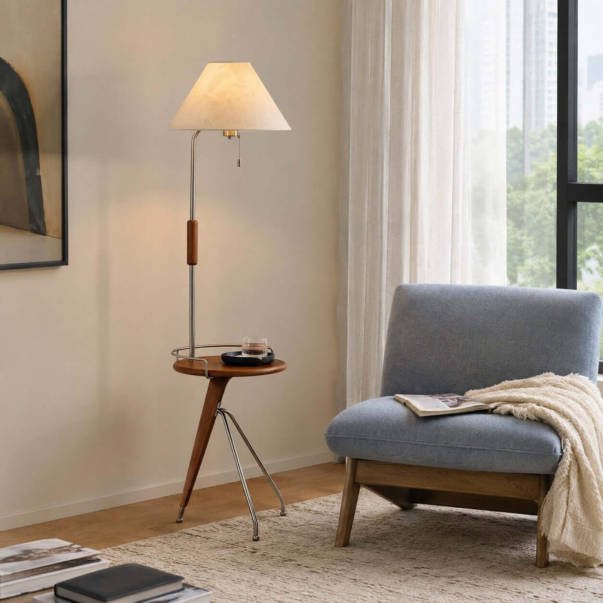 Beige-shaded Clérachic floor lamp with a tray table by a window, next to a blue-grey lounge chair and a knitted throw.