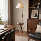 Clérachic floor lamp with a tray holding a book, between a wooden desk and a dark leather armchair near shelves.