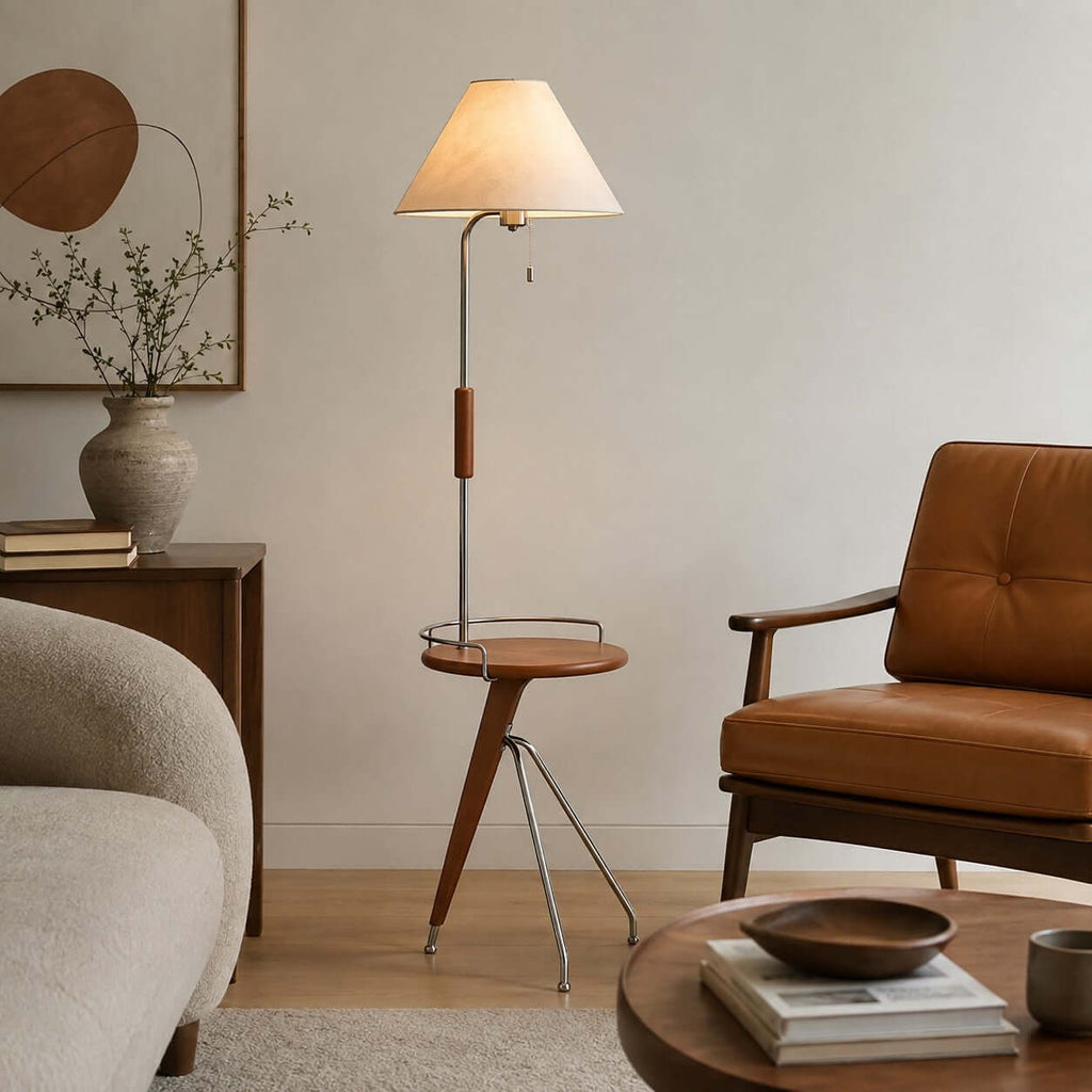 Tripod base and wood tray of this Clérachic floor lamp, beside a tan leather armchair and a ceramic vase.