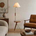 Tripod base and wood tray of this Clérachic floor lamp, beside a tan leather armchair and a ceramic vase.