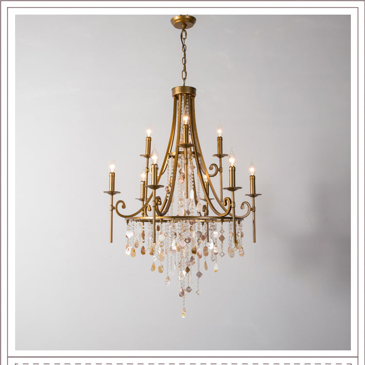 The Clérachic Trove chandelier in brass, tiered arms lit above a cascade of natural alabaster and crystal drops.