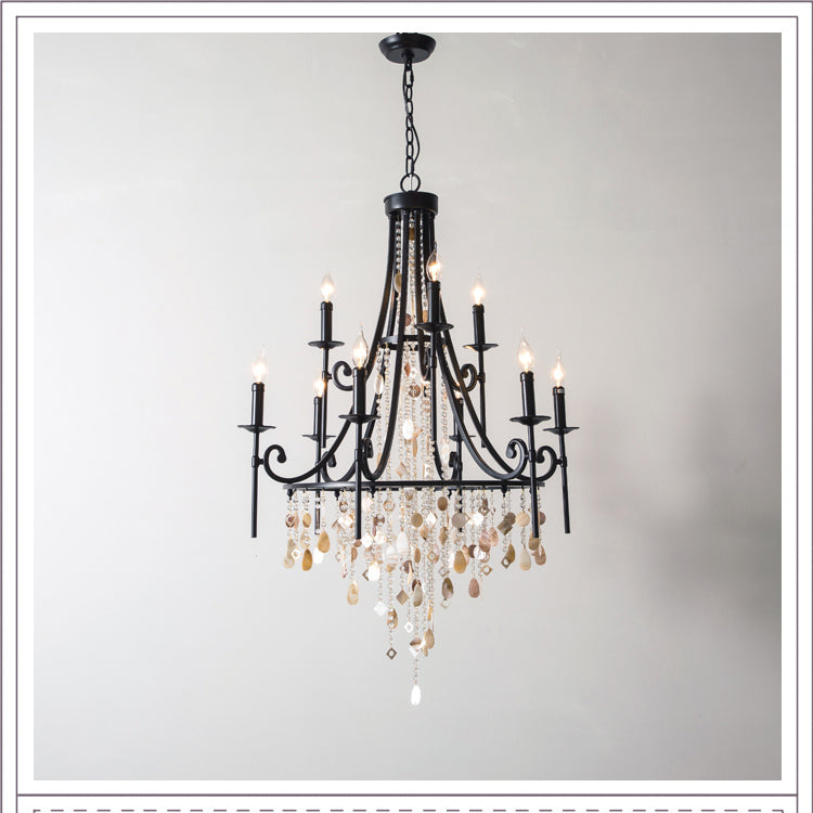 Clérachic Trove shown in the black finish, candle arms lit over a fall of amber-toned alabaster slices.