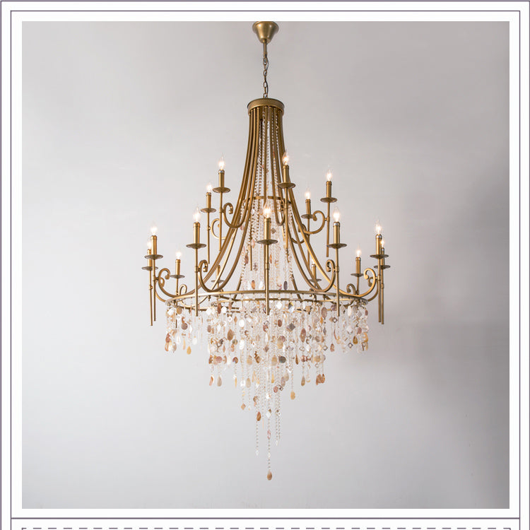 The Clérachic Trove in brass at a grand size, stone strands falling well below the lit candle arms.