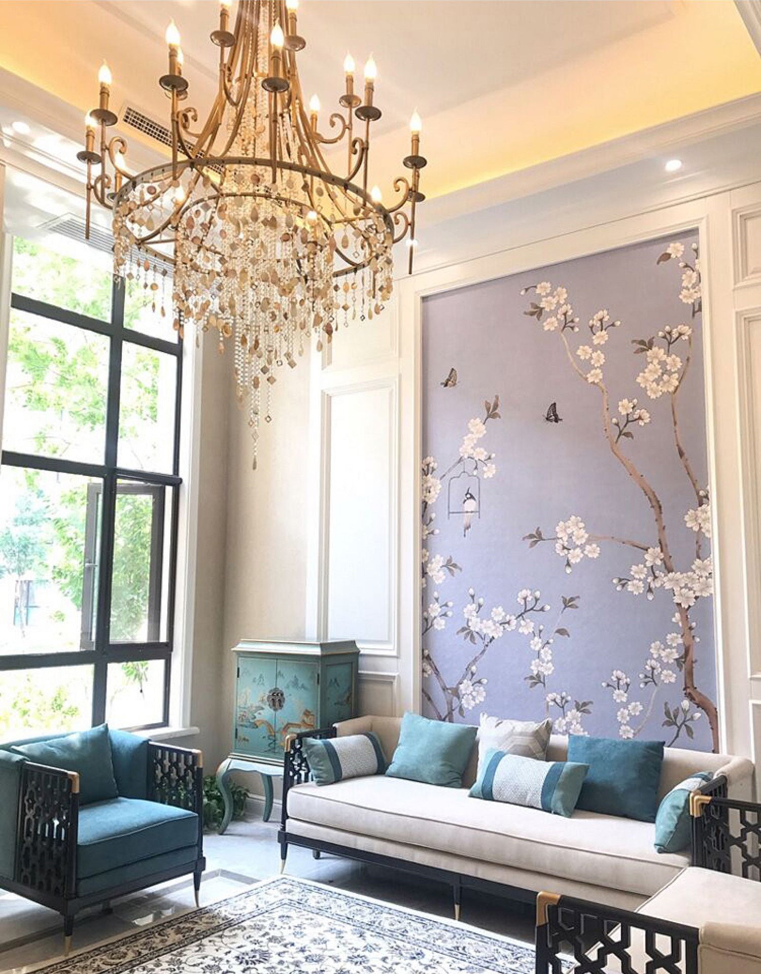 The Clérachic Trove hung in a bright room with blossom wallpaper, teal sofas set beneath its lit arms.