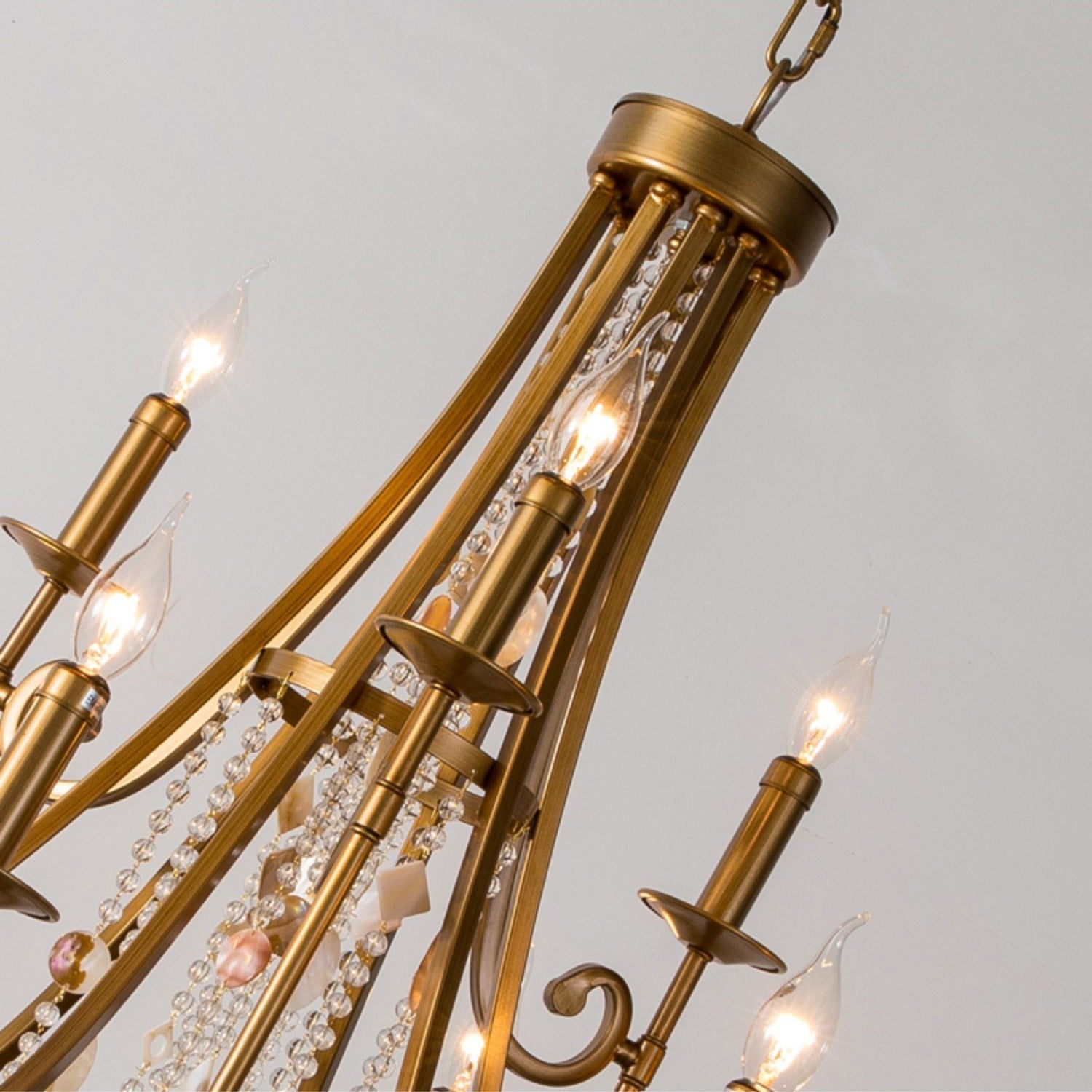 Close view of the Clérachic Trove's brass candle arms and the crystal strands threaded between them.