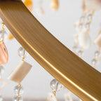 Detail of the Clérachic Trove's brushed brass ring, with alabaster slices and clear beads hanging from it.