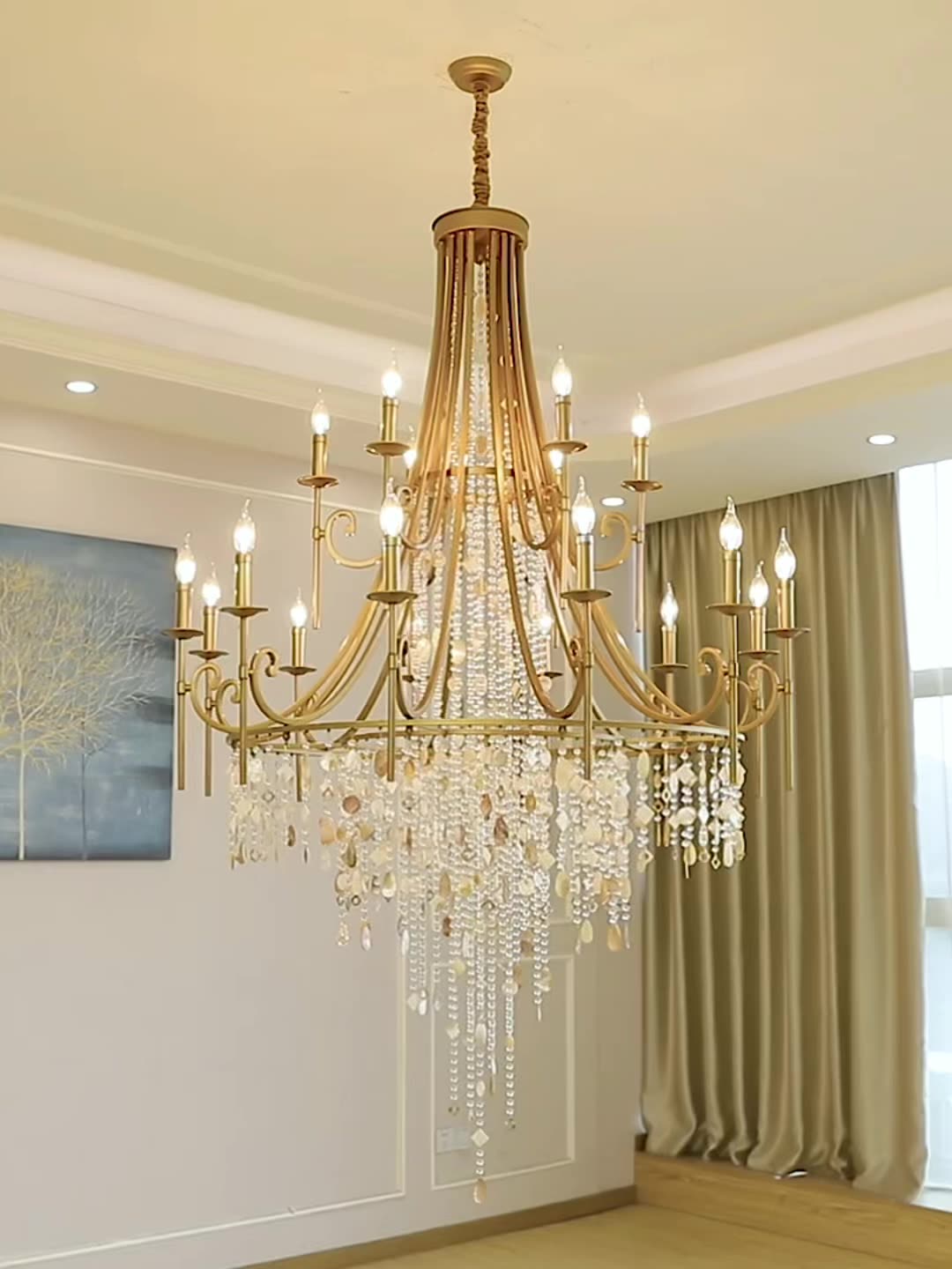 The Clérachic Trove in brass lit above a dining room, its glow picking up the green drapes behind.