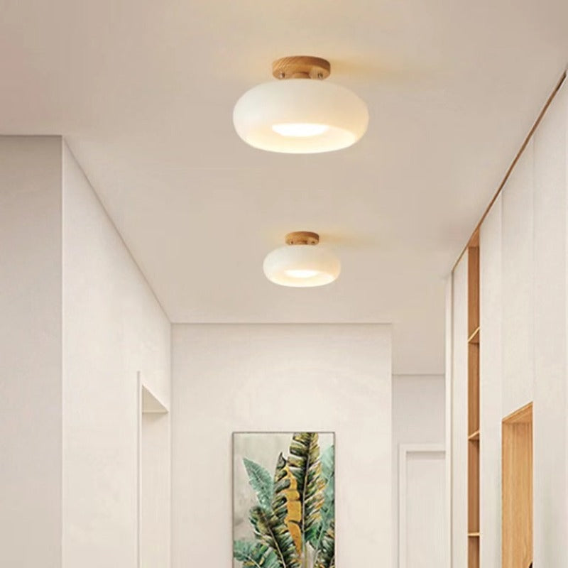 Clérachic turned wood ceiling light in white opal glass, two of them fitted along a bright hallway ceiling above a framed leaf print.