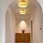 The Clérachic turned wood ceiling light lit in mustard glass, washing a warm pool of light down the wall onto an oak sideboard.
