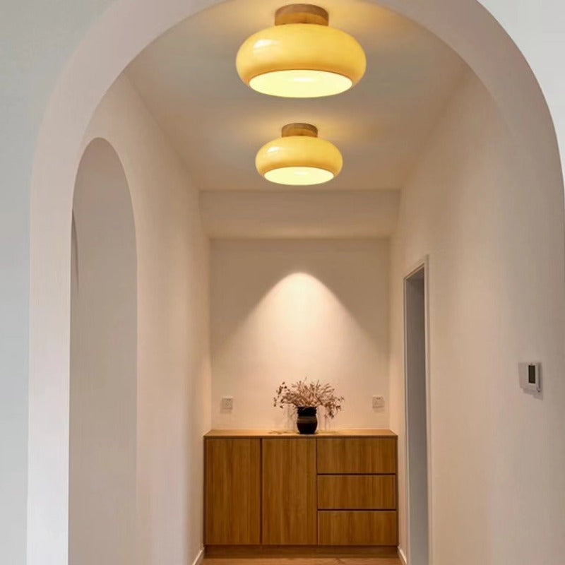 The Clérachic turned wood ceiling light lit in mustard glass, washing a warm pool of light down the wall onto an oak sideboard.