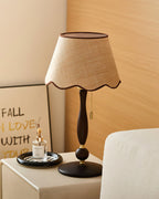 A lamp with a brass pull chain stands on a cream cabinet in front of an oak wall, with a framed lettered print behind; a Clérachic design.