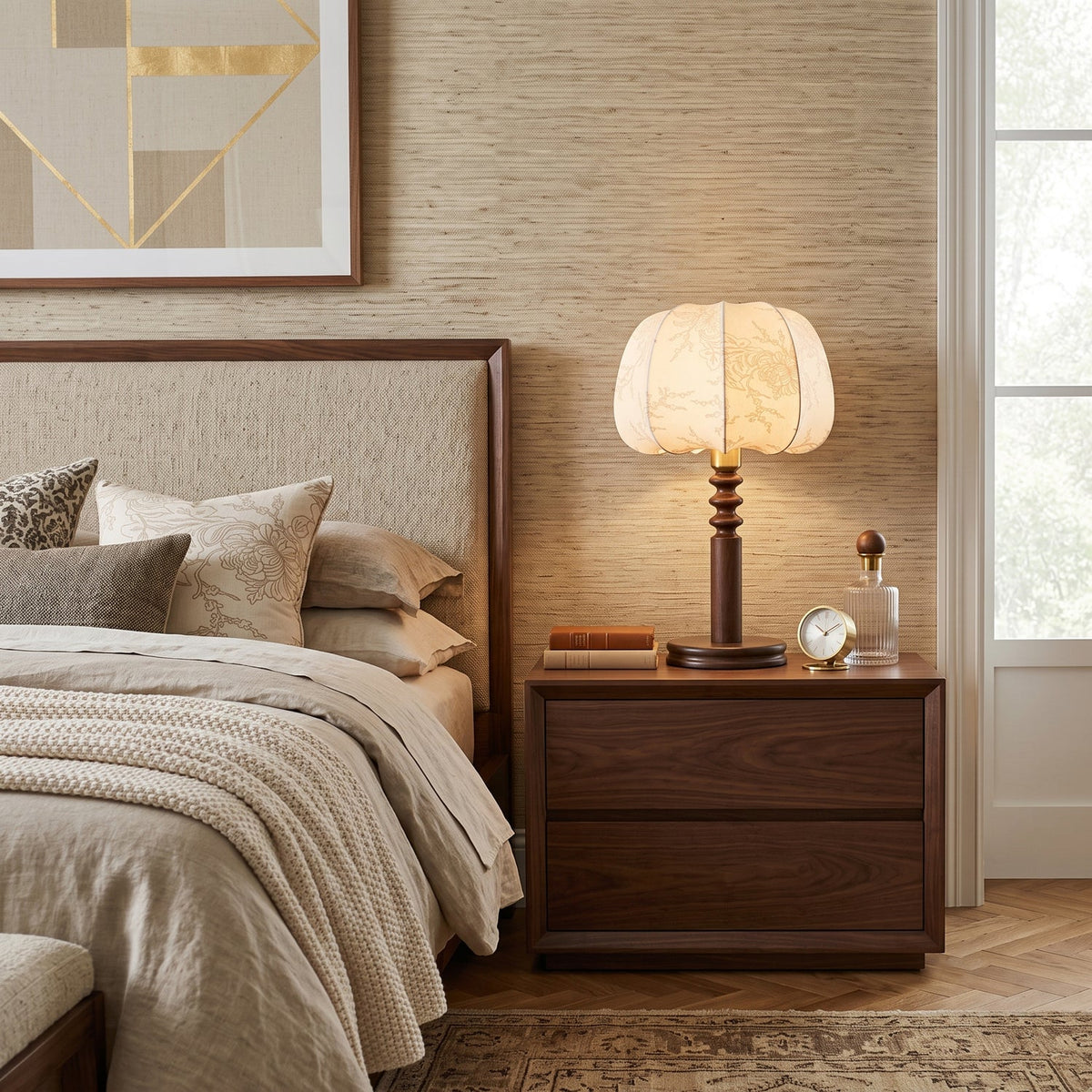 Beside a bed with linen bedding, a Clérachic table lamp glows on a walnut nightstand next to a small clock and glass bottle.