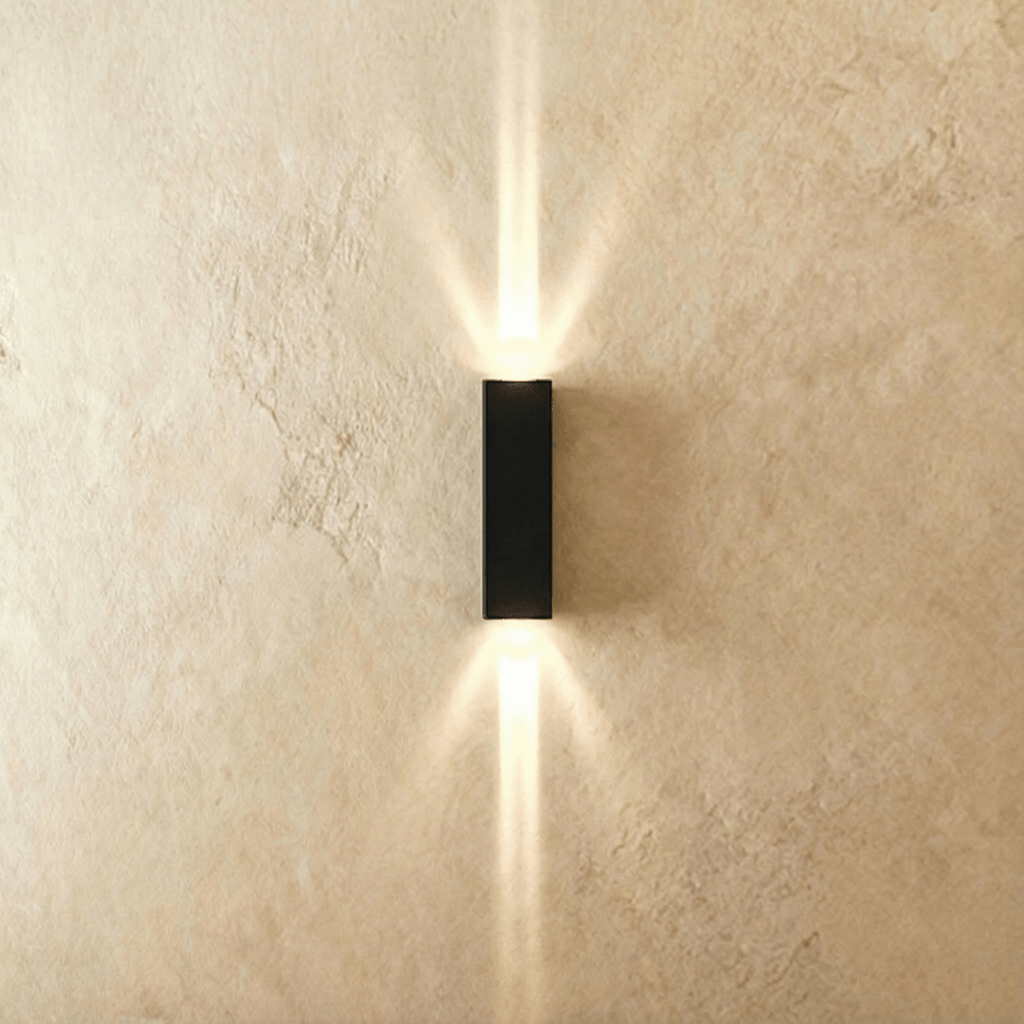 This Clérachic outdoor wall light in black aluminium projects twin beams of warm light up and down a plastered wall.