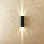 This Clérachic outdoor wall light in black aluminium projects twin beams of warm light up and down a plastered wall.