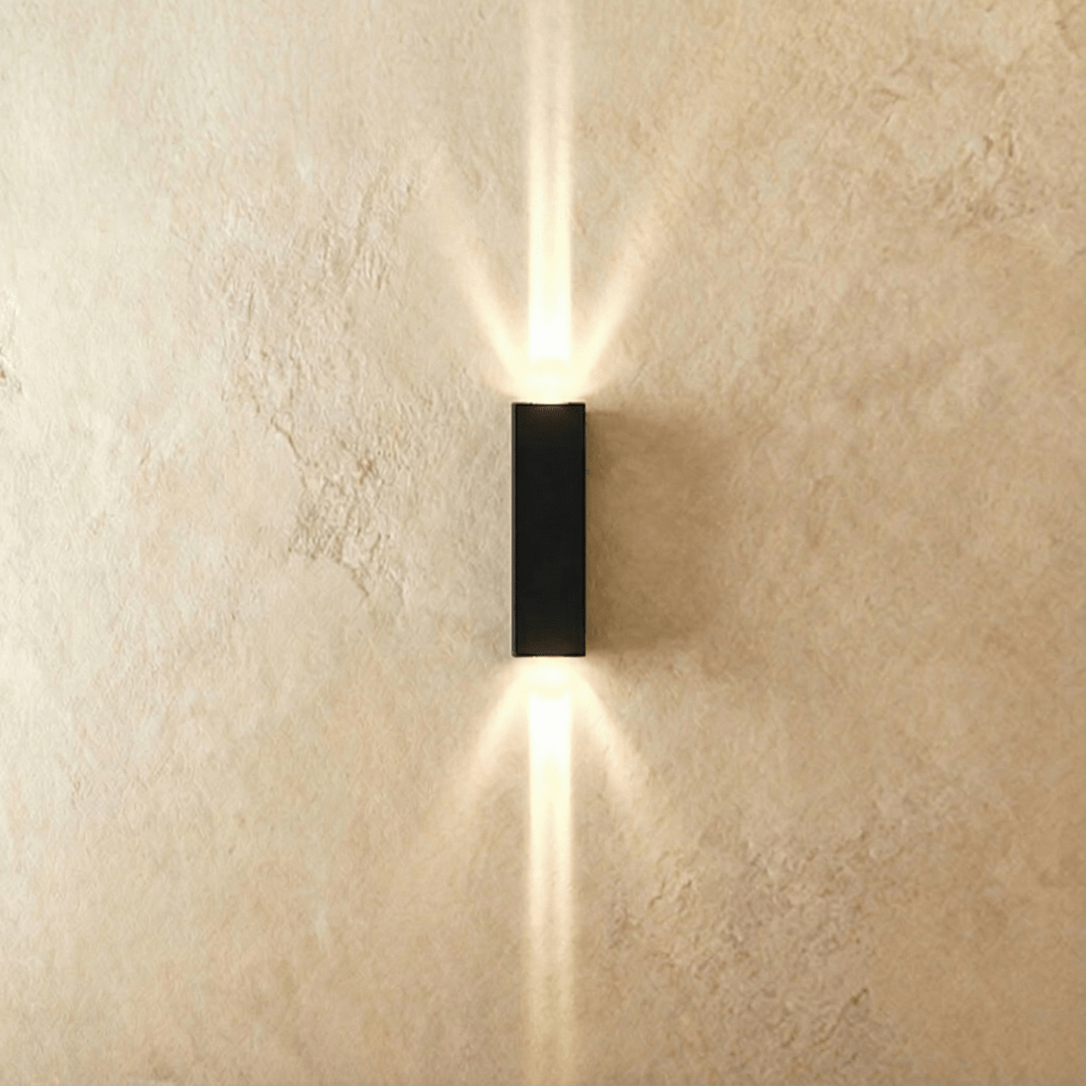 This Clérachic outdoor wall light in black aluminium projects twin beams of warm light up and down a plastered wall.