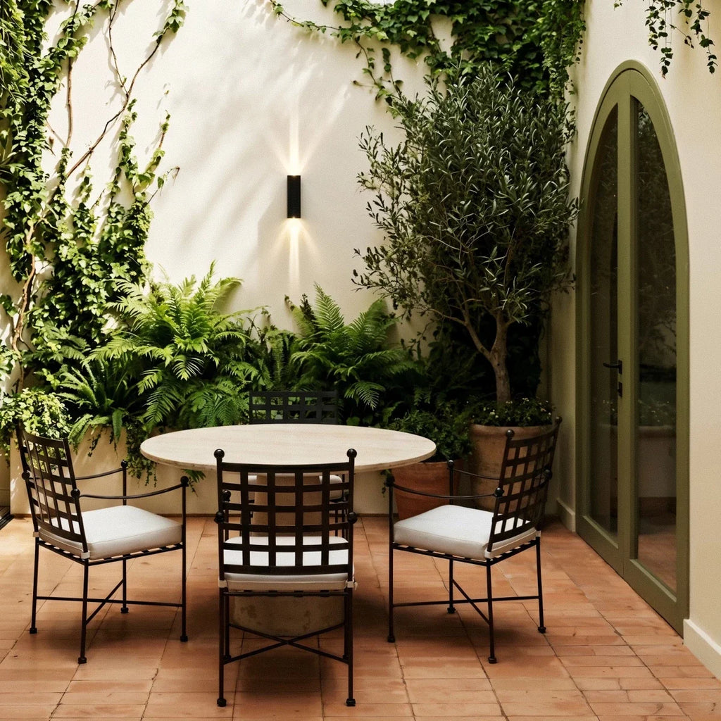 On an ivy-covered courtyard wall, the twin-beam Clérachic outdoor wall light lights a patio dining set from above.