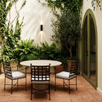 On an ivy-covered courtyard wall, the twin-beam Clérachic outdoor wall light lights a patio dining set from above.