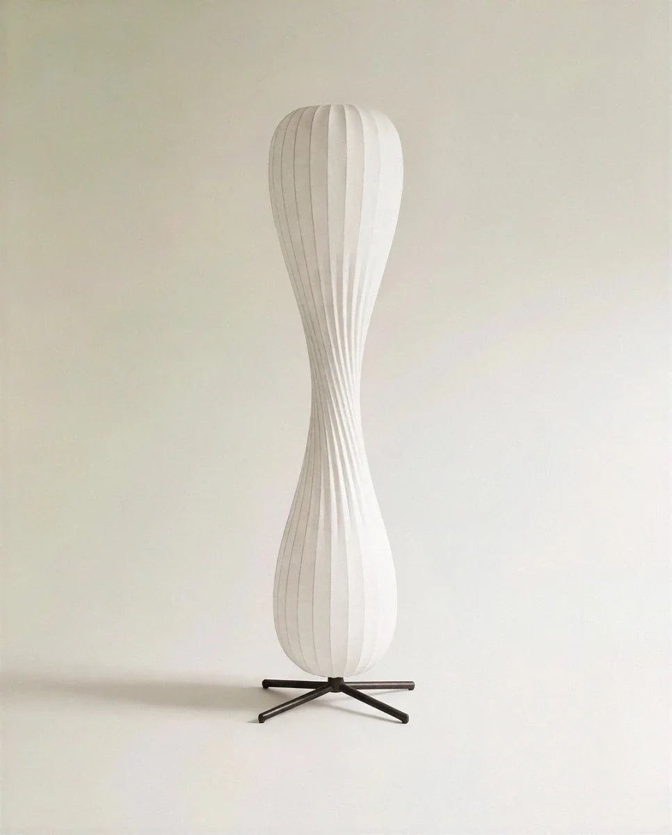 Clérachic twisted hourglass floor lamp with a ribbed paper-style shade on a black four-legged metal base, unlit on pale grey.