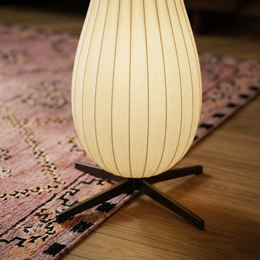 Clérachic close-up of the lit lower shade resting on its black four-legged base over a pink rug and oak floor.