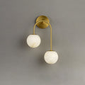 Brass finish of the Clérachic Two-Globe Alabaster Wall Sconce, the round wall plate and single curved arm carrying both stone globes.