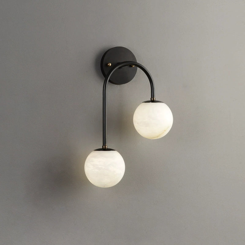 Black metalwork on the Clérachic Two-Globe Alabaster Wall Sconce draws a clean dark line between its two off-white alabaster globes.