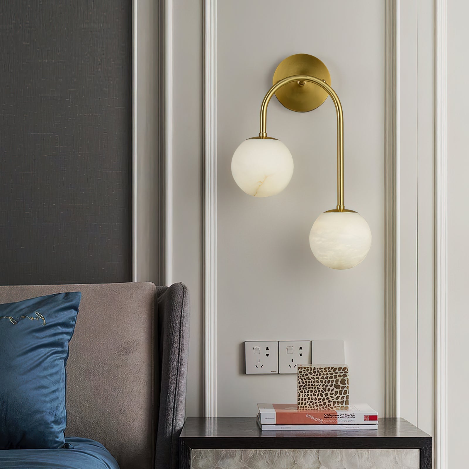 Brass Clérachic Two-Globe Alabaster Wall Sconce on a panelled bedroom wall, freeing the bedside table below for books and a small box.