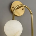 Close-up of the Clérachic Two-Globe Alabaster Wall Sconce showing the brushed brass wall plate, the curved arm and the veining in one globe.