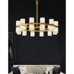 The Clérachic Two-Ring Chandelier on its rigid brass rod, seen head-on above a cream buttoned sofa in a dark room.