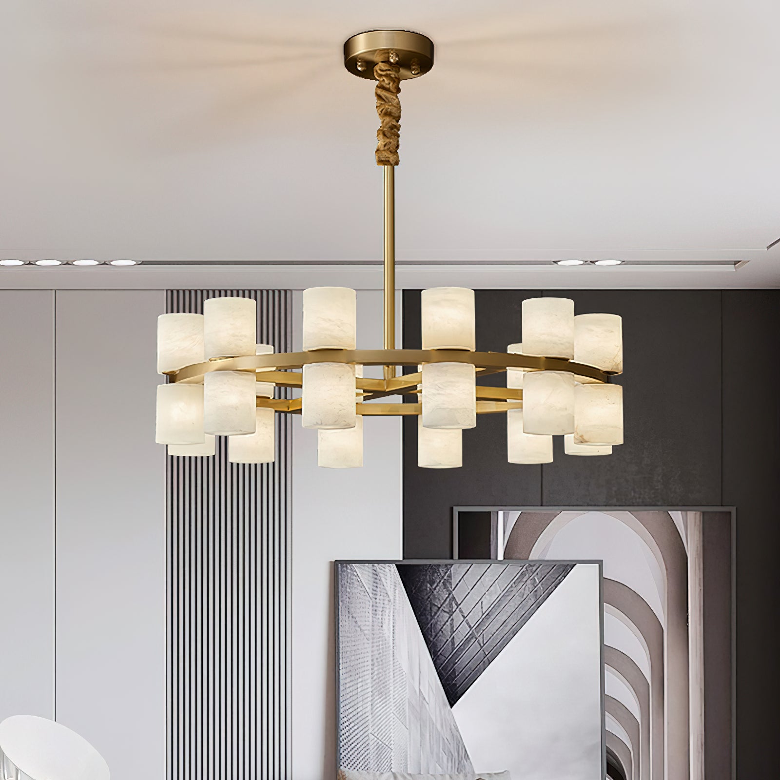 Clérachic Two-Ring Chandelier lit low under a plain ceiling in a modern grey room, framed prints leaning below.