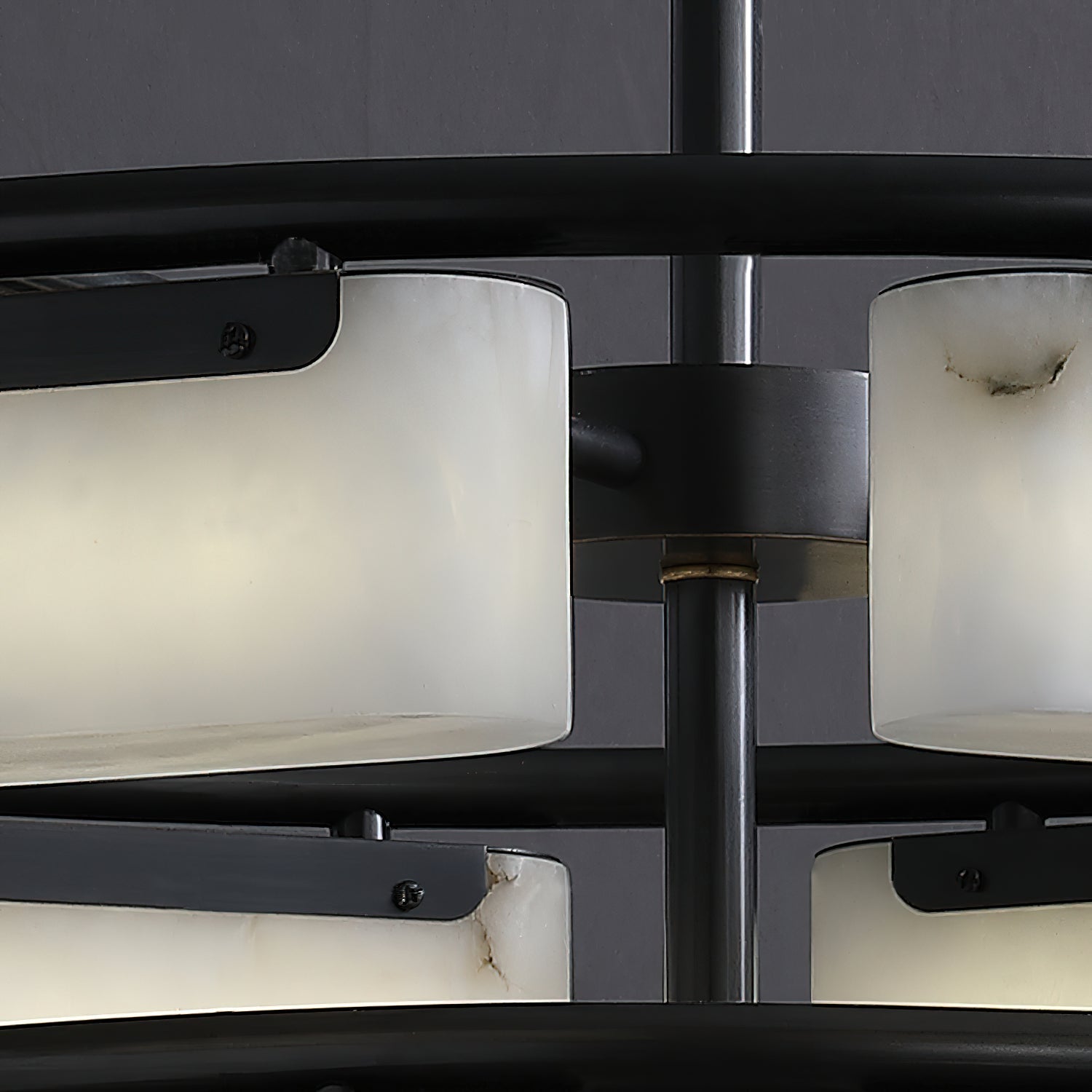 Close view of the Clérachic alabaster ring chandelier hub, where a brass collar meets the matte black stem between the two tiers.