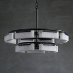 The Clérachic Two-Tier Alabaster Ring Chandelier unlit against a grey plaster wall, showing its stacked ring silhouette.