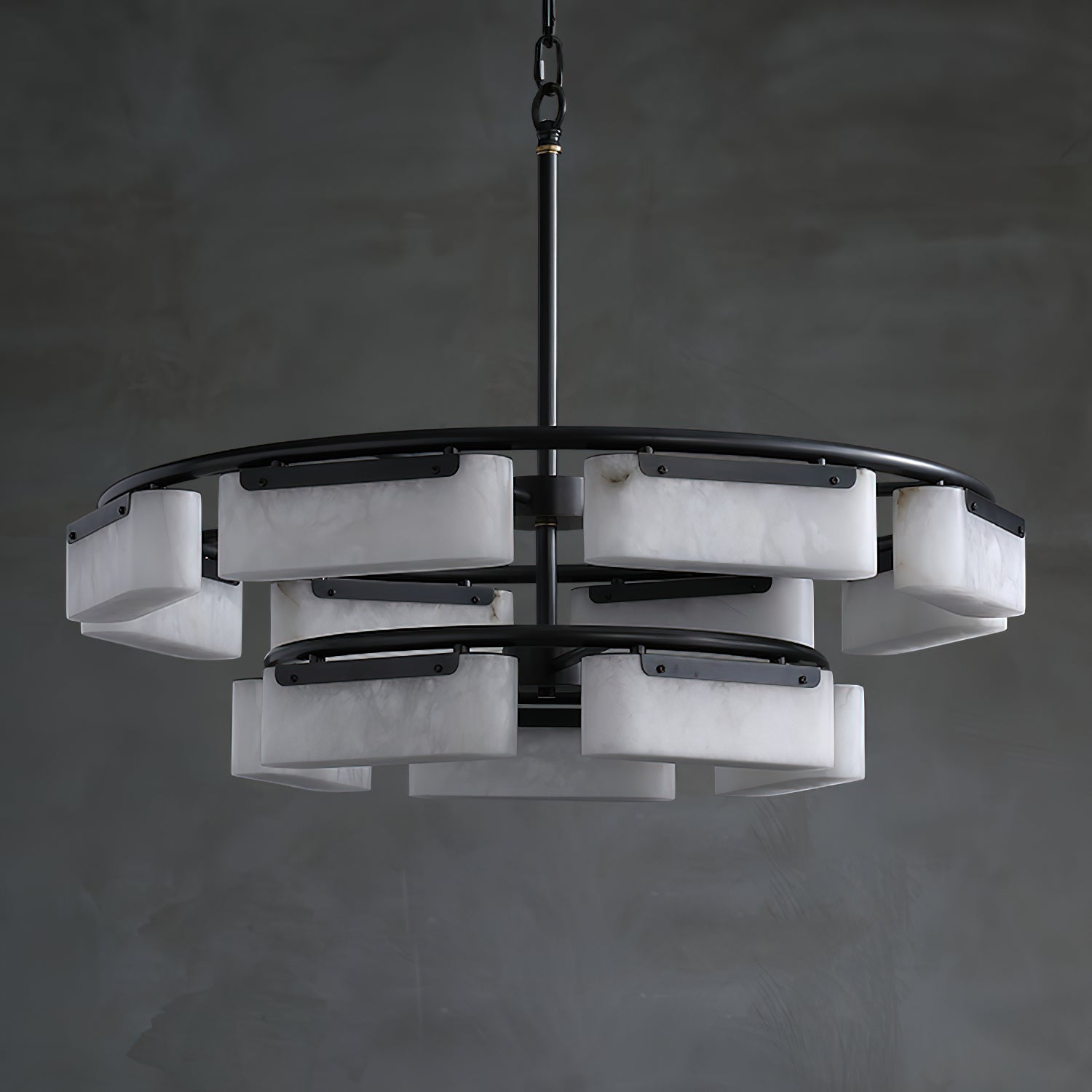The Clérachic Two-Tier Alabaster Ring Chandelier unlit against a grey plaster wall, showing its stacked ring silhouette.