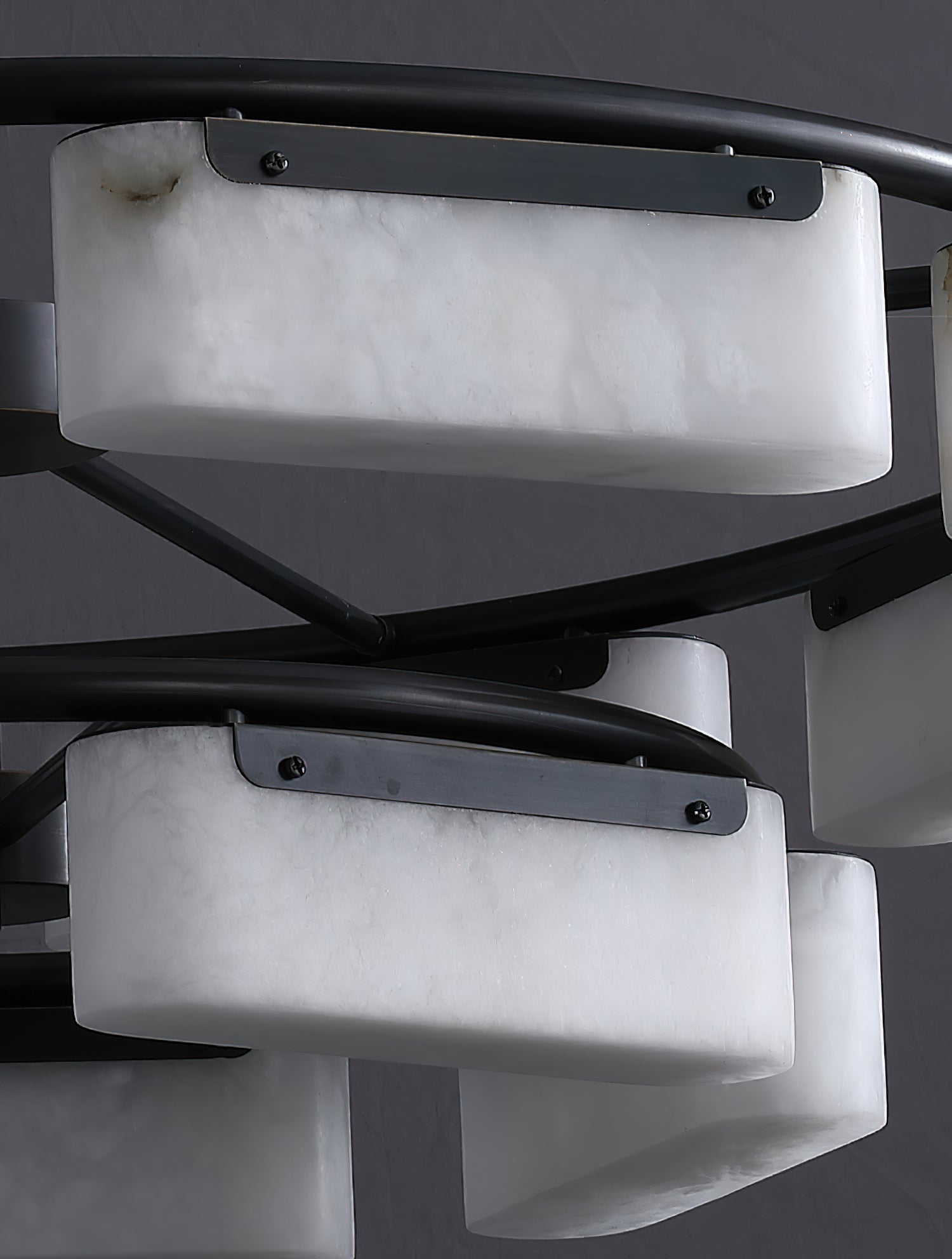 Detail of the Clérachic alabaster ring chandelier, each stone shade held by a brushed metal strap screwed to the black frame.
