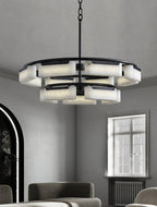 Clérachic Two-Tier Alabaster Ring Chandelier lit above a dining table in a tall room with a window and an arched black door.