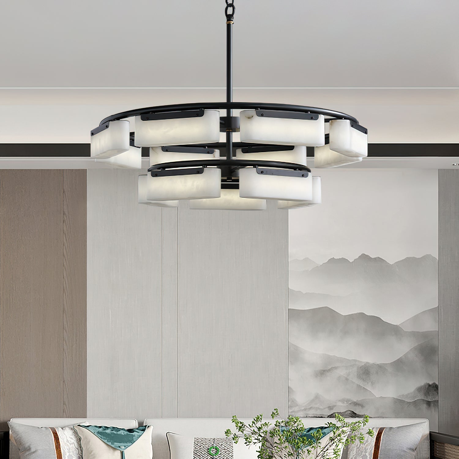 The Clérachic alabaster ring chandelier lit above a living-room sofa, its stone shades warm against an ink-wash mountain mural.